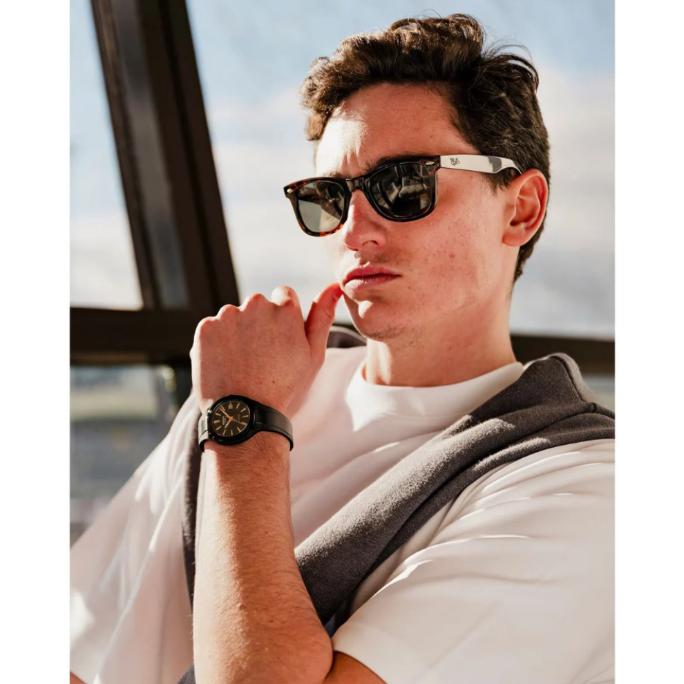Man wearing sunglasses and a watch, with a blurred background